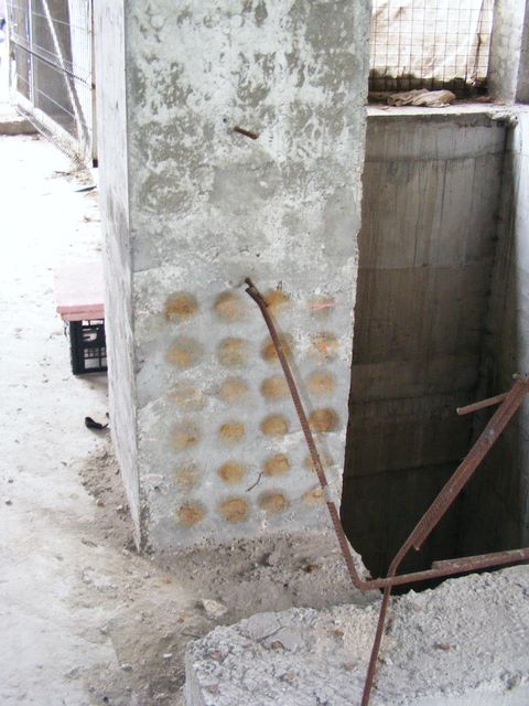 Stâlp de beton cu puncte de încercare, lângă o deschidere în planșeu cu armături ieșite.